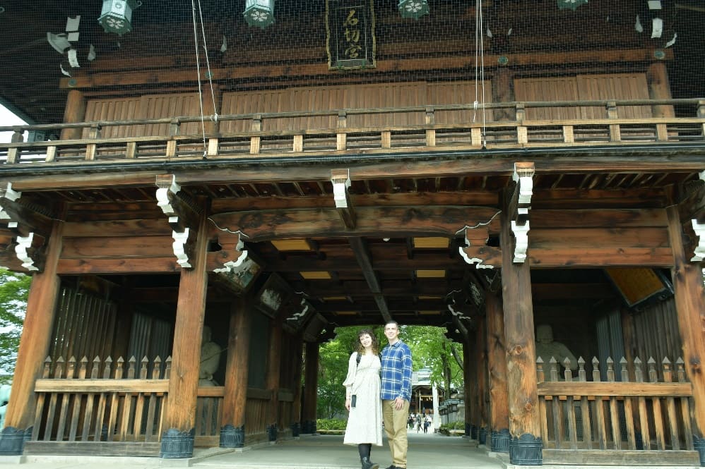 The main gate to the shrine, beautifully adorned with rustic carvings and statues of Japanese gods, welcomes visitors with a sense of timeless tradition.